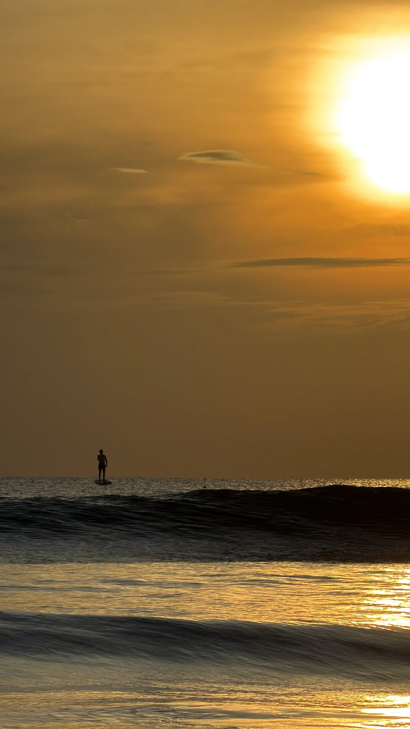 A rider flying an electric hydrofoil above the sea at sunset in Da Nang
